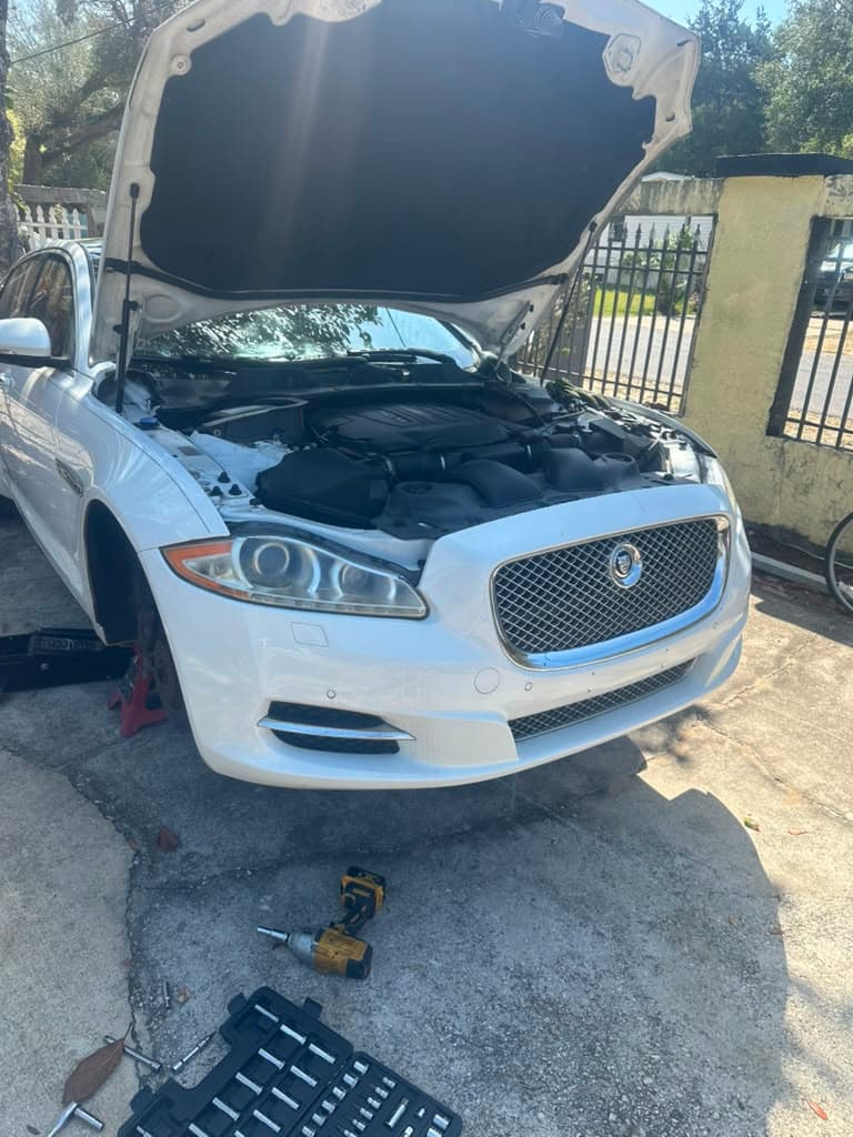 Jaguar XJ serviced on-site, hood open in customer's driveway